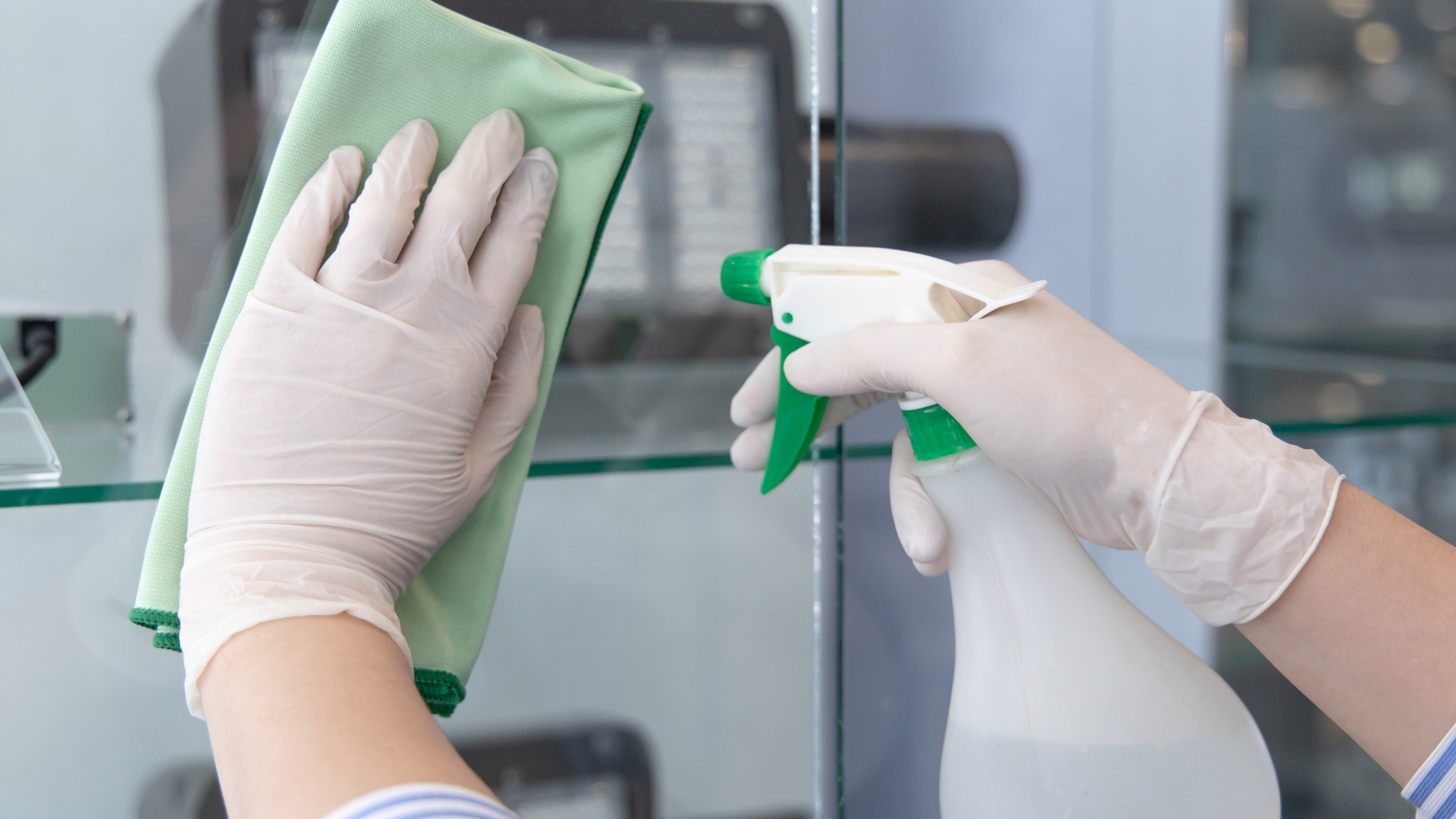 A person with gloves and gloves on holding a bottle of cleaner