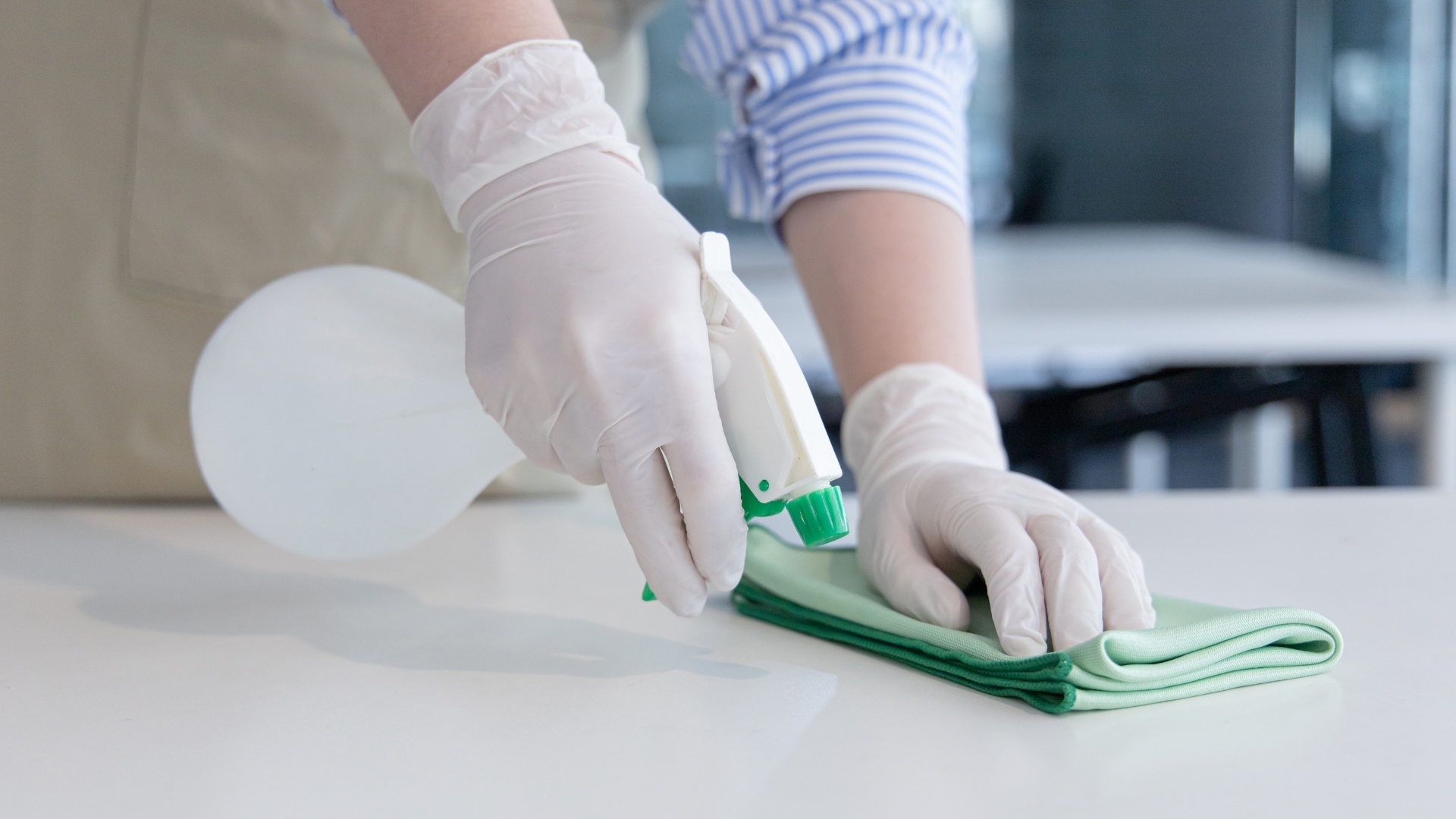 A person with gloves and gloves cleaning a table