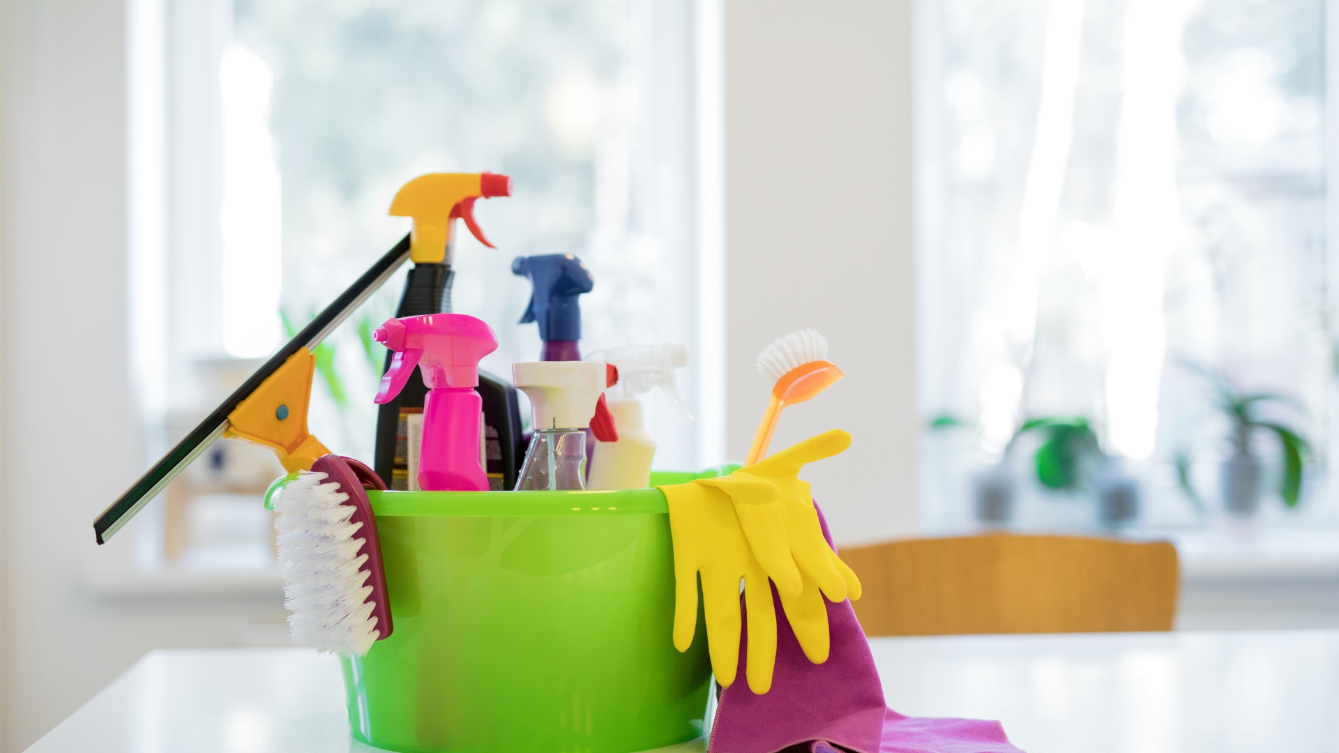 A green bucket filled with cleaning supplies on top of a table