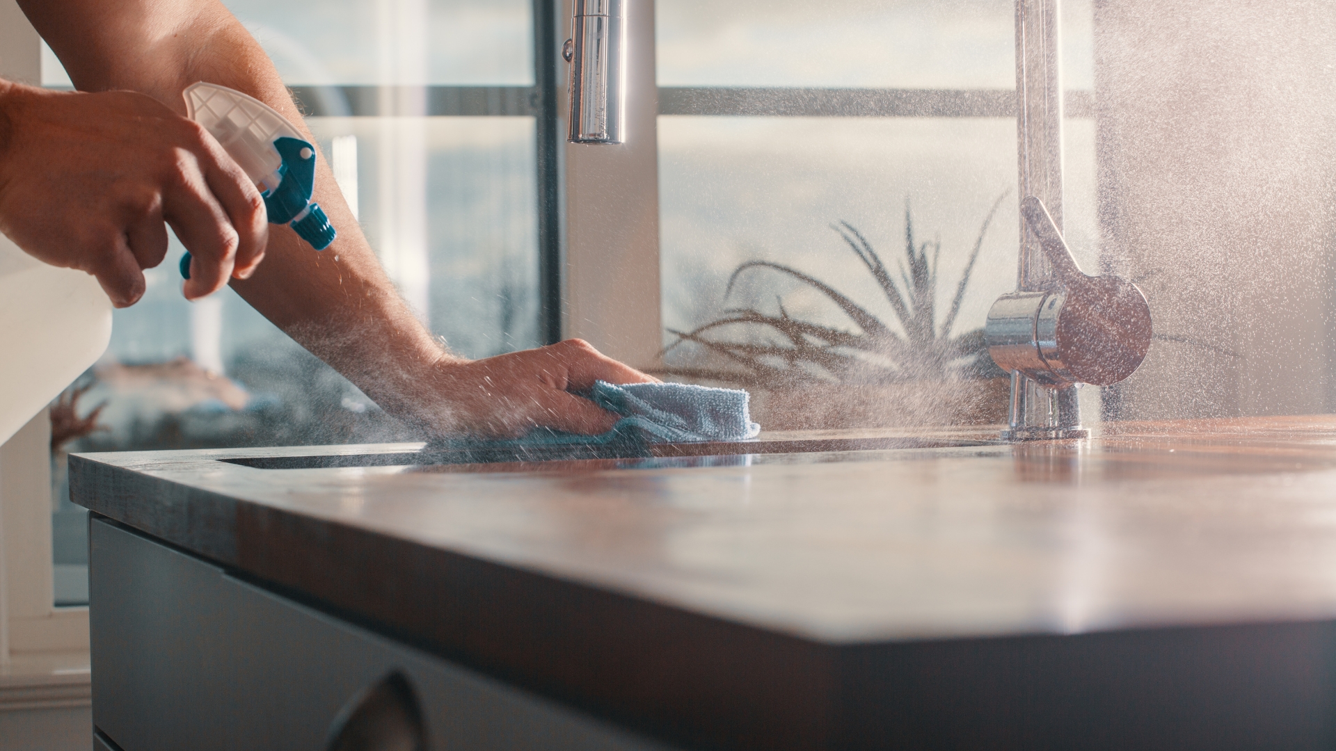 A person is cleaning a kitchen sink with a rag